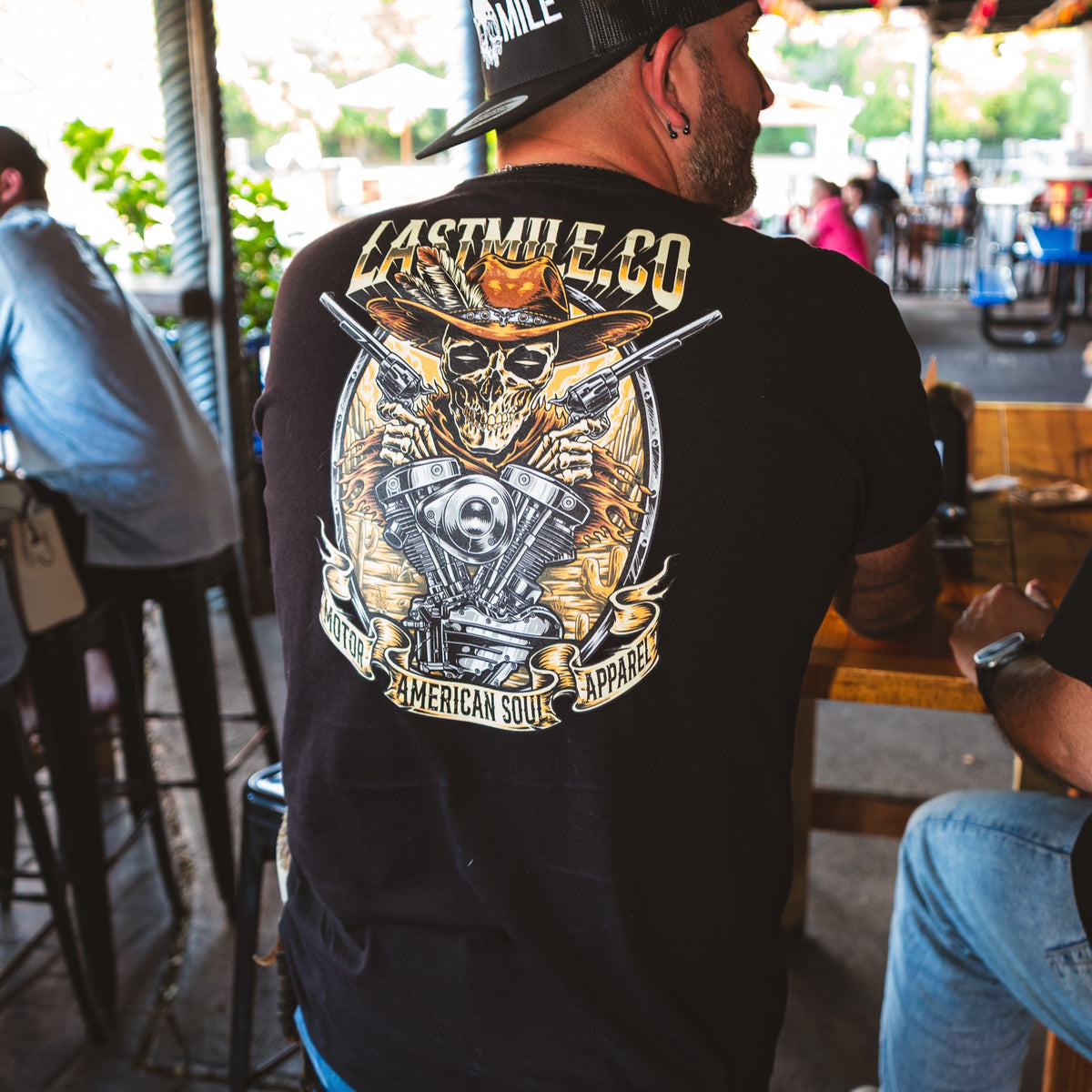 Built to Last Tee men's motorcycle t-shirt back print, second angle on a bar patio