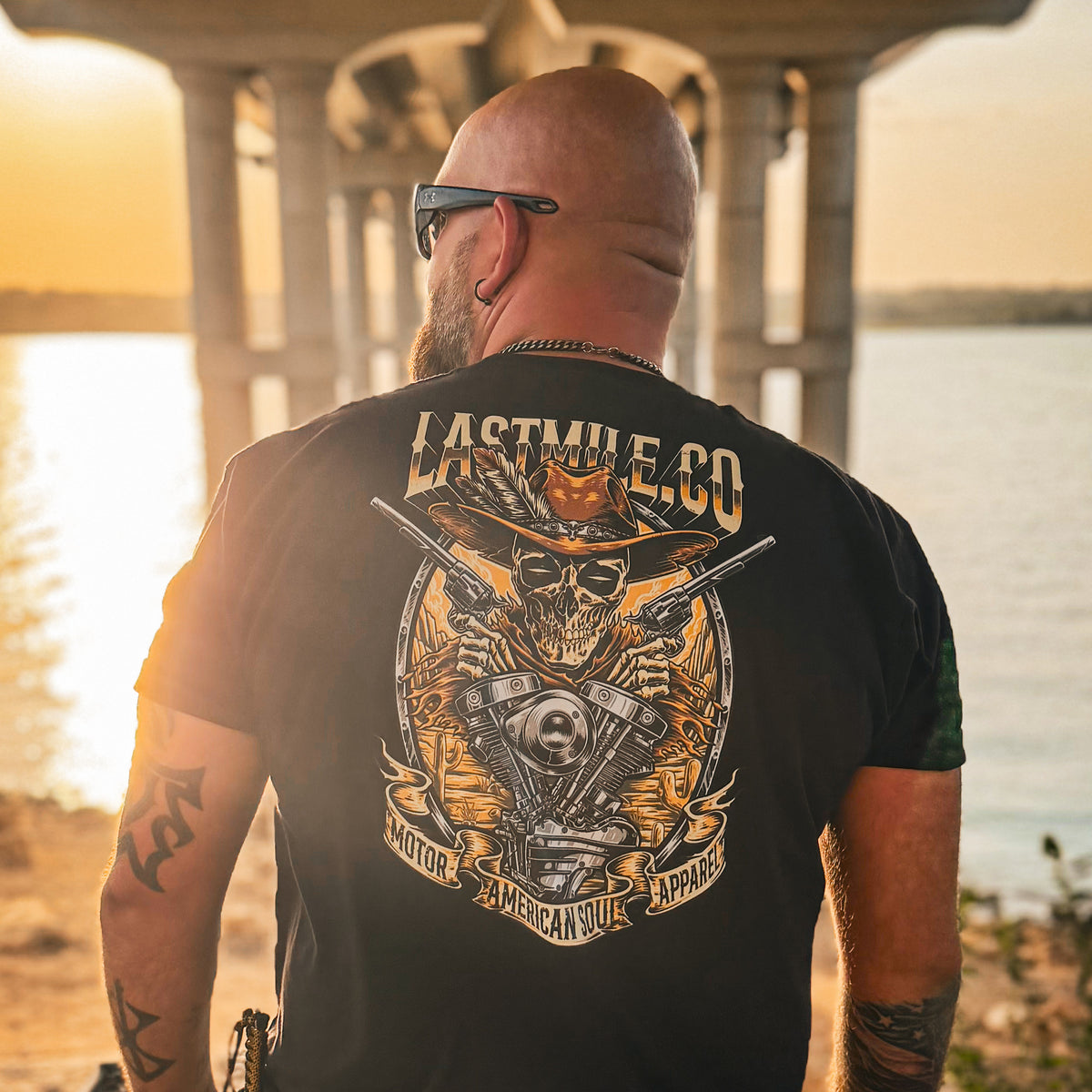 Built to Last Tee men's motorcycle t-shirt worn under a bridge at sunset, skull in a cowboy hat back print