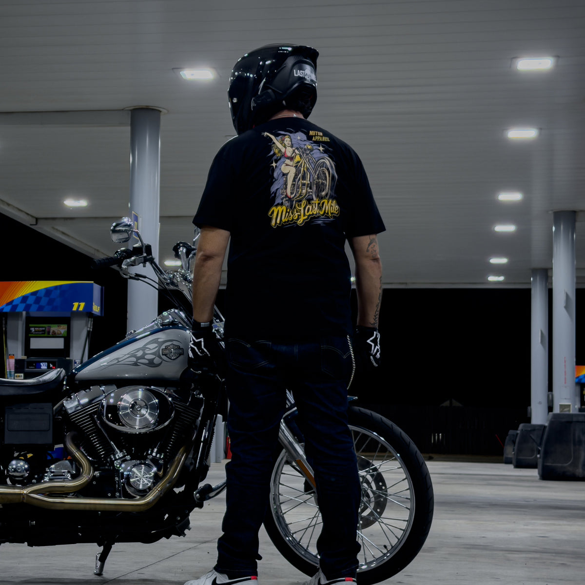 Miss Last Mile Tee men's motorcycle t-shirt back print shown on a rider at a gas station at night