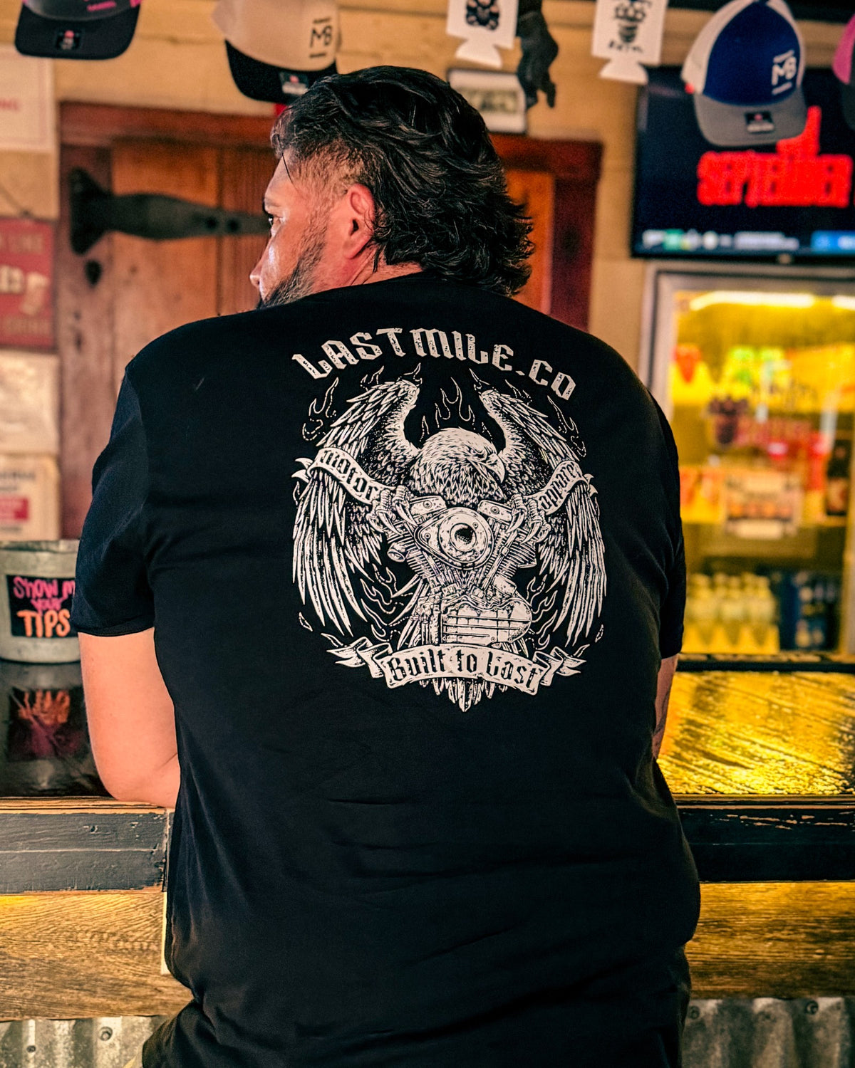 Wing and Iron Tee, worn by a rider, back graphic at the bar counter